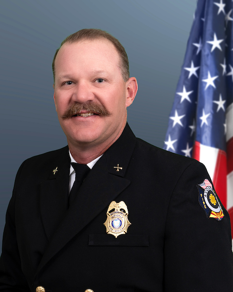 Battalion Chief Evan Titterington wearing his class "A"s with an American flag behind him