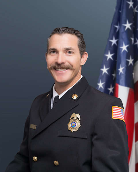 Battalion Chief Steve Mayhew wearing his Class "A"s with an American flag in the background
