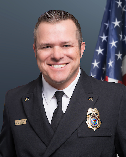 Battalion Chief Garry Siler wearing his class "A"s with an American flag behind him